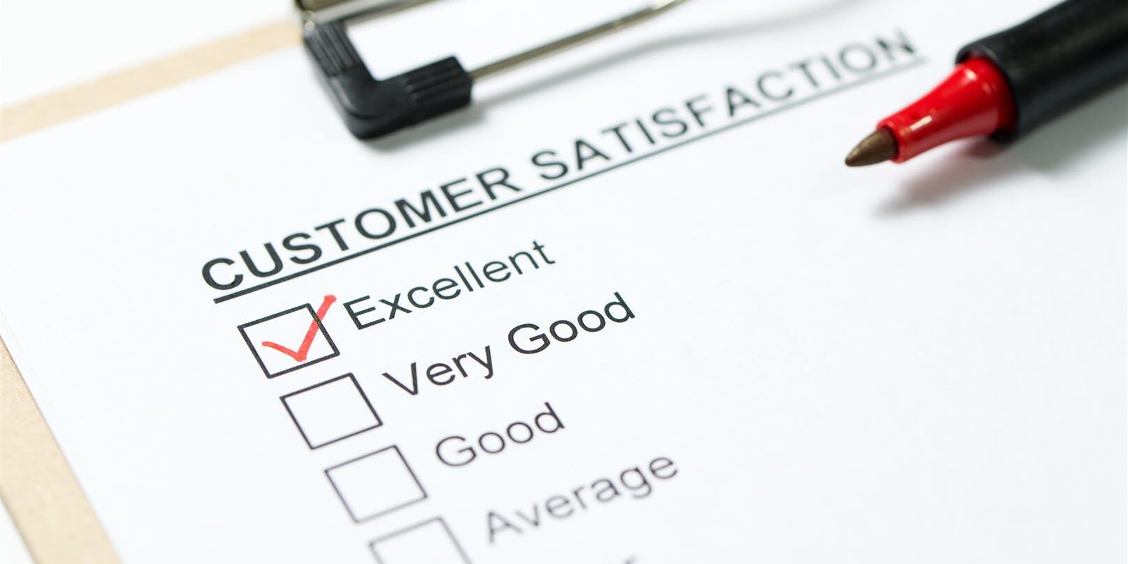 Customer satisfaction survey form on clipboard with red pen Customer satisfaction survey form on clipboard with red pen